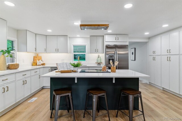 1815 Ingalls St, Lakewood, CO 80214 - kitchen featuring stainless steel fridge with ice dispenser, a breakfast bar area, light wood finished floors, light countertops, and recessed lighting