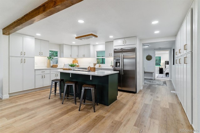 1815 Ingalls St, Lakewood, CO 80214 - kitchen featuring stainless steel refrigerator with ice dispenser, a breakfast bar, light wood-style flooring, light countertops, and white cabinets
