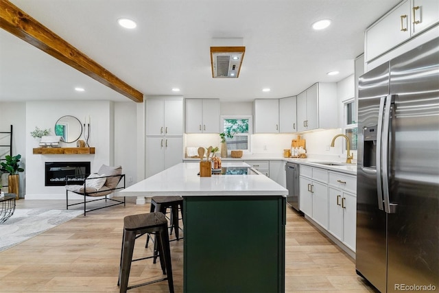 1815 Ingalls St, Lakewood, CO 80214 - kitchen featuring stainless steel appliances, a sink, light wood finished floors, a breakfast bar, and a kitchen island