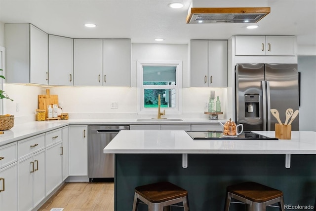 1815 Ingalls St, Lakewood, CO 80214 - kitchen with appliances with stainless steel finishes, a breakfast bar, a sink, light countertops, and recessed lighting