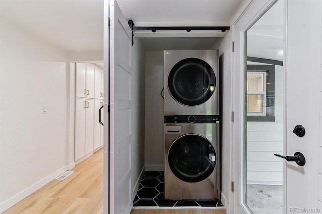 1815 Ingalls St, Lakewood, CO 80214 - laundry room with stacked washer / drying machine, baseboards, wood finished floors, and a barn door