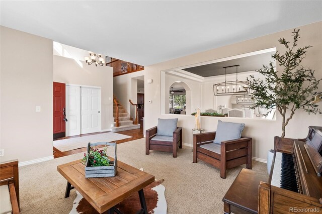 living room with arched walkways, light colored carpet, stairway, and an inviting chandelier