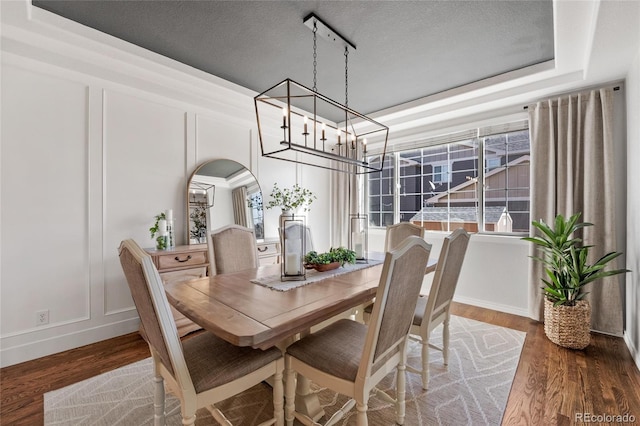 dining room featuring arched walkways, a decorative wall, and wood finished floors