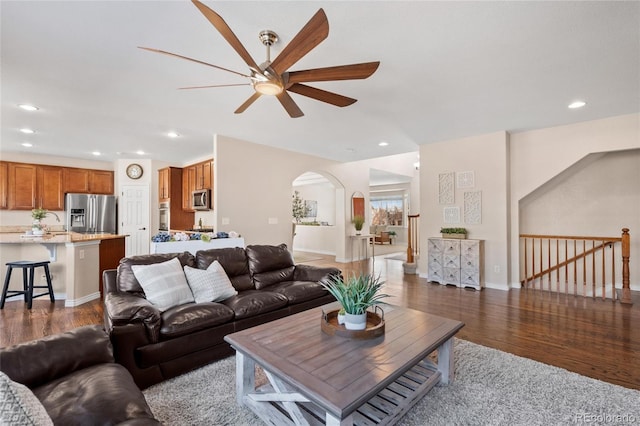 living area featuring arched walkways, ceiling fan, wood finished floors, and recessed lighting