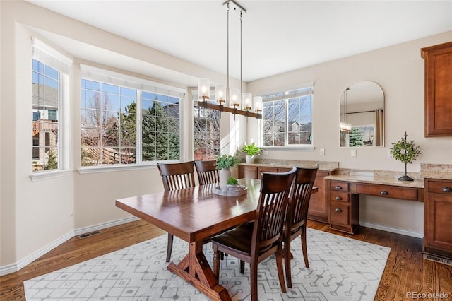 dining area with an inviting chandelier, visible vents, baseboards, and wood finished floors