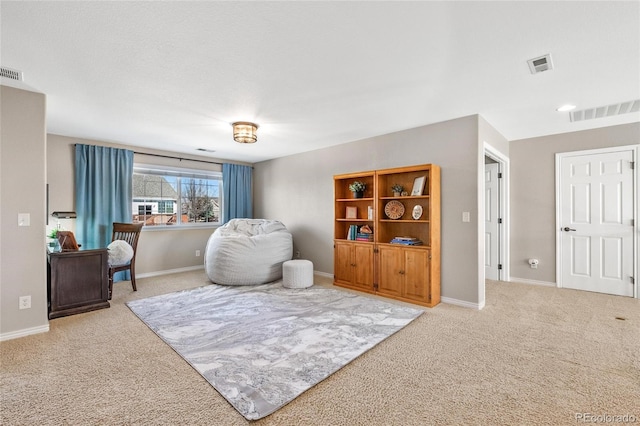 sitting room with carpet floors, visible vents, and baseboards