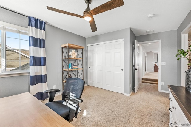 office featuring light carpet, a ceiling fan, visible vents, and baseboards