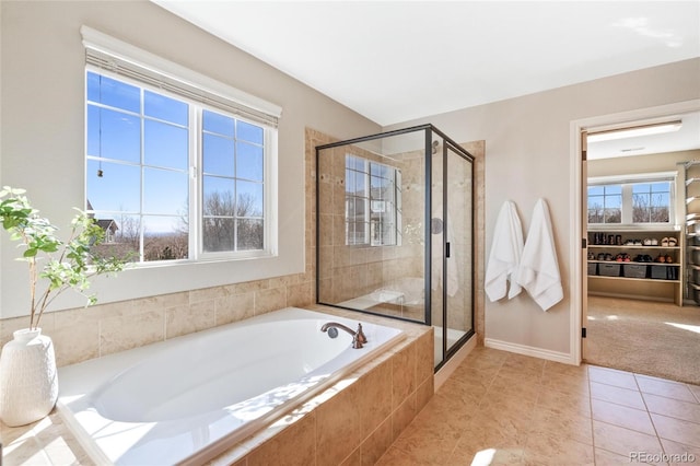 bathroom with a stall shower, tile patterned flooring, a garden tub, and baseboards