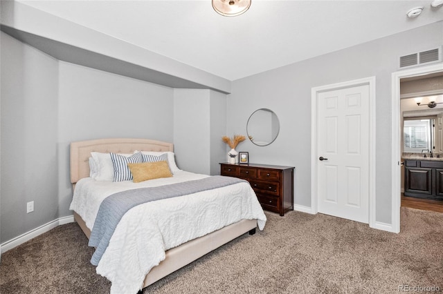 bedroom with carpet floors, visible vents, a sink, and baseboards