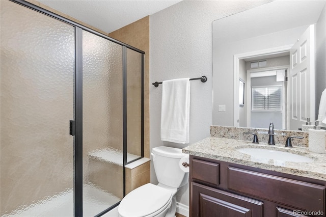 bathroom featuring toilet, a textured wall, a shower stall, and vanity