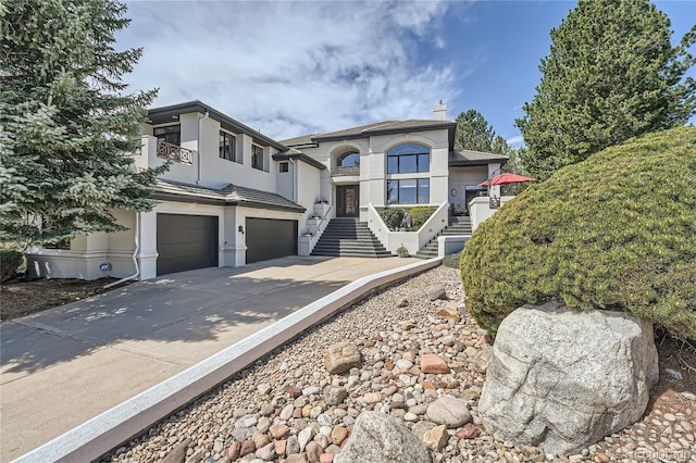 6961 Salvia St, Arvada, CO 80007 - view of front of home with an attached garage, stairs, driveway, a chimney, and stucco siding