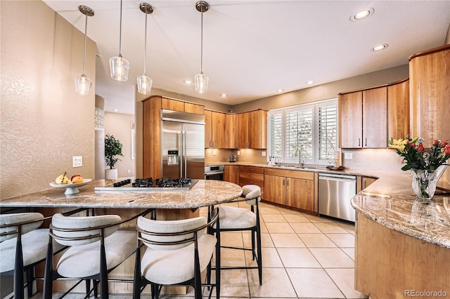 6961 Salvia St, Arvada, CO 80007 - kitchen featuring appliances with stainless steel finishes, a peninsula, recessed lighting, a kitchen breakfast bar, and light stone countertops