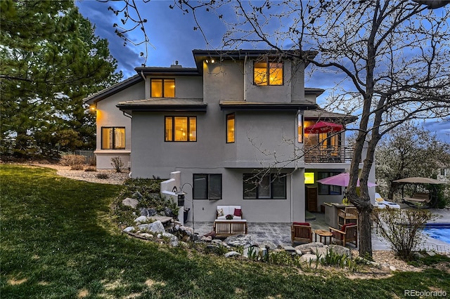 6961 Salvia St, Arvada, CO 80007 - rear view of house featuring a balcony, a lawn, stucco siding, and a patio