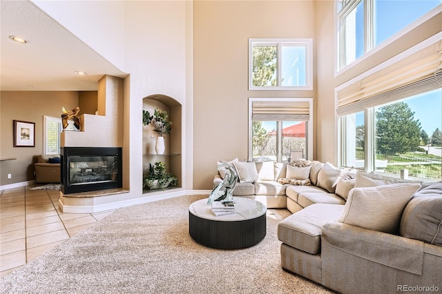 6961 Salvia St, Arvada, CO 80007 - tiled living room featuring a towering ceiling, a multi sided fireplace, and recessed lighting