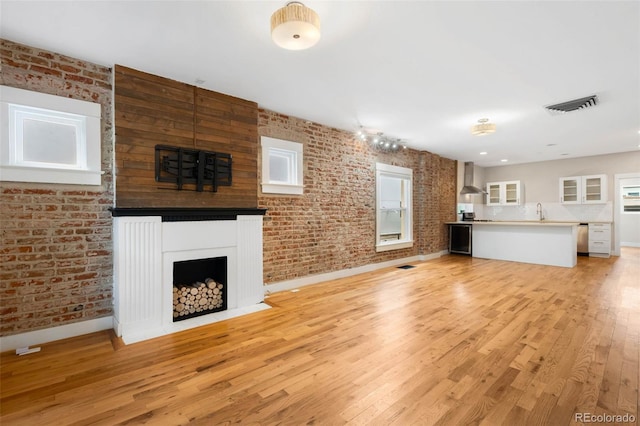 1753 W 36th Ave, Denver, CO 80211 - unfurnished living room with a fireplace, brick wall, and light wood finished floors