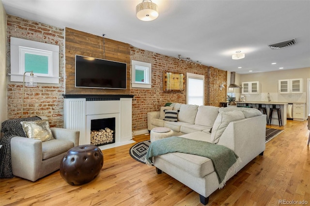 1753 W 36th Ave, Denver, CO 80211 - living area featuring brick wall, light wood-style flooring, a fireplace, and recessed lighting