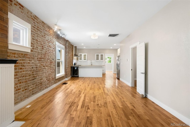 1753 W 36th Ave, Denver, CO 80211 - unfurnished living room featuring brick wall and light wood finished floors