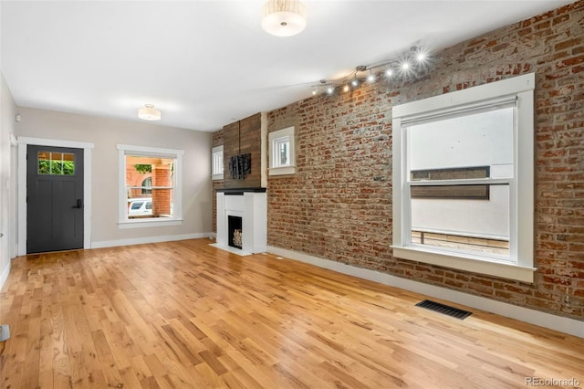 1753 W 36th Ave, Denver, CO 80211 - unfurnished living room with light wood-type flooring, a large fireplace, and brick wall