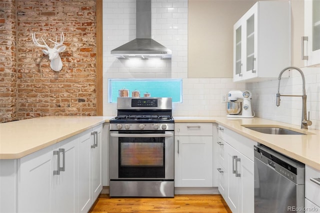 1753 W 36th Ave, Denver, CO 80211 - kitchen featuring wall chimney exhaust hood, appliances with stainless steel finishes, backsplash, glass insert cabinets, and light countertops