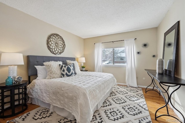 bedroom featuring a textured ceiling, light wood-type flooring, and baseboards