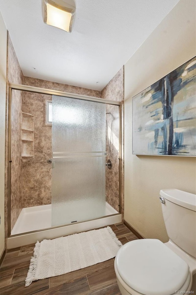 full bathroom featuring a stall shower, toilet, and wood tiled floor