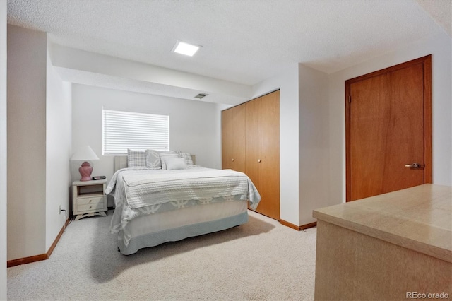 bedroom featuring light carpet, a closet, a textured ceiling, and baseboards