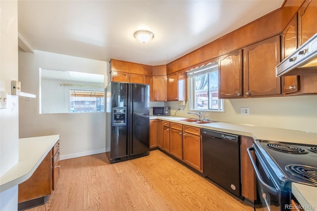 kitchen featuring exhaust hood, sink, black appliances, and light wood-type flooring