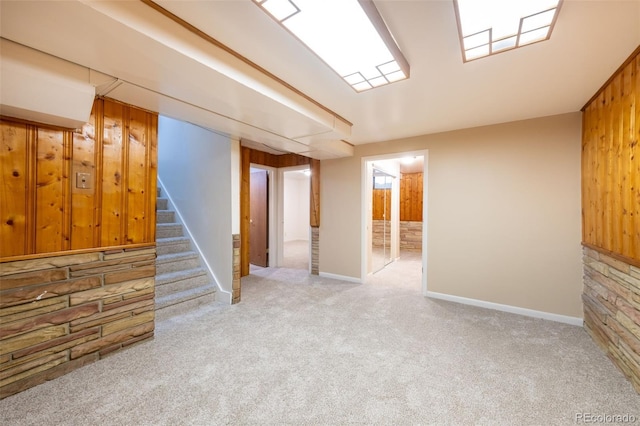 basement featuring light carpet and wood walls