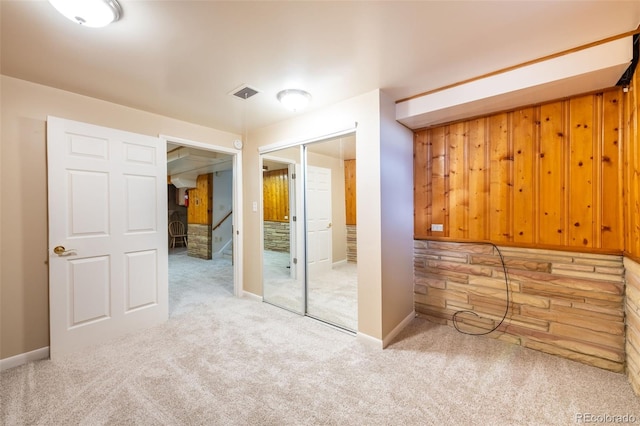 empty room featuring carpet and wood walls