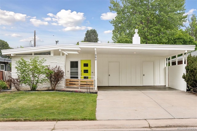 260 S Jasmine St, Denver, CO 80224 - mid-century modern home featuring an attached carport, concrete driveway, a front lawn, a chimney, and board and batten siding