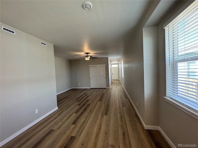 hallway featuring visible vents, baseboards, and wood finished floors