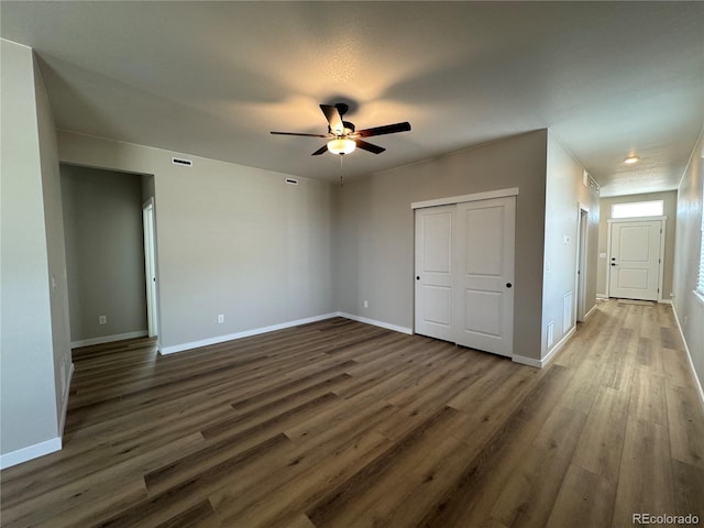 unfurnished bedroom featuring visible vents, ceiling fan, baseboards, a closet, and dark wood-style floors