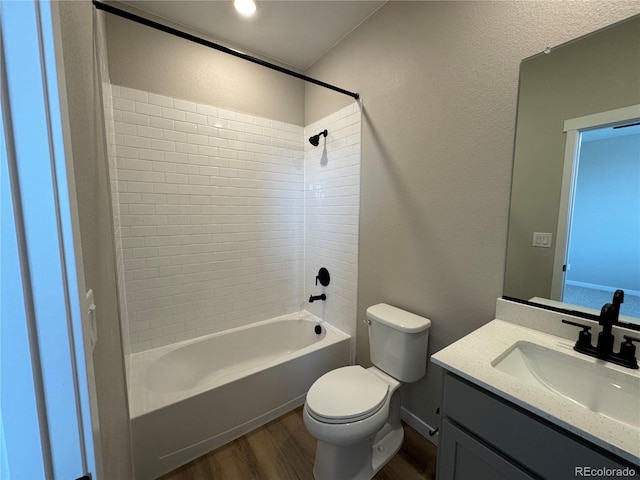 bathroom featuring toilet, wood finished floors, bathing tub / shower combination, vanity, and a textured wall