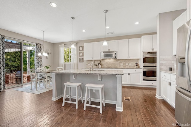 kitchen with white cabinetry, stainless steel appliances, and light stone counters