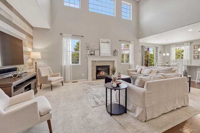 living room featuring a tiled fireplace, a towering ceiling, and light wood-type flooring