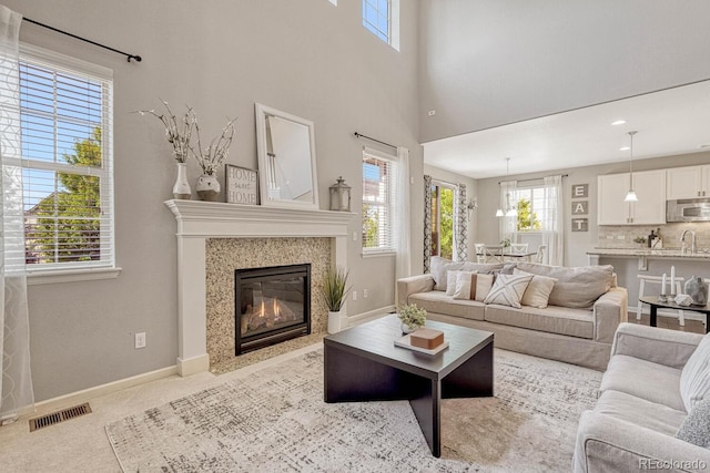 living room with a healthy amount of sunlight, sink, light carpet, and a high ceiling