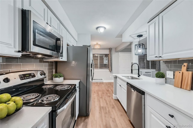 kitchen with white cabinets, stainless steel appliances, sink, and decorative light fixtures