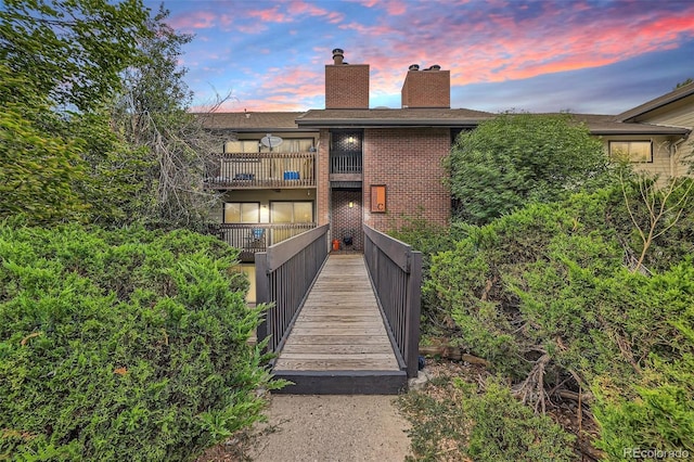 back house at dusk featuring a balcony