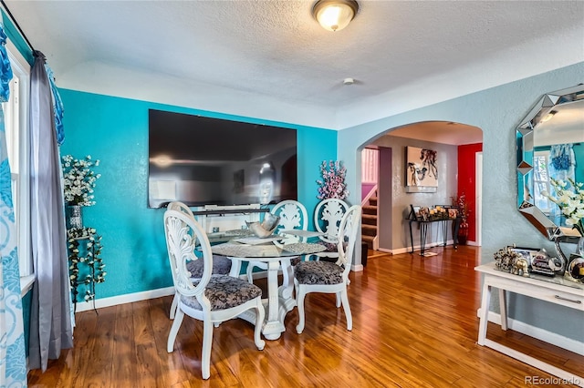 655 S Perry St, Denver, CO 80219 - dining space featuring baseboards, arched walkways, wood finished floors, and a textured ceiling