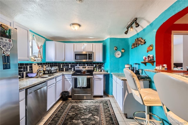 655 S Perry St, Denver, CO 80219 - kitchen featuring tasteful backsplash, a sink, a textured ceiling, stainless steel appliances, and light tile patterned flooring