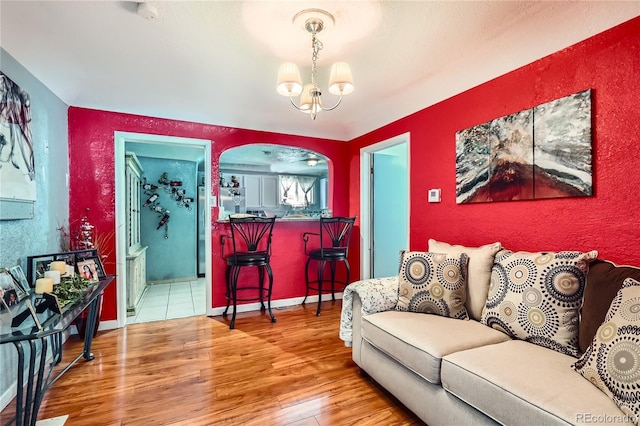 655 S Perry St, Denver, CO 80219 - living area featuring arched walkways, a notable chandelier, and wood finished floors