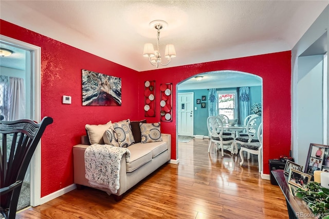 655 S Perry St, Denver, CO 80219 - living room with wood-type flooring, baseboards, arched walkways, and an inviting chandelier