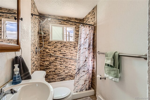 655 S Perry St, Denver, CO 80219 - full bathroom with toilet, a wealth of natural light, a stall shower, and a textured ceiling