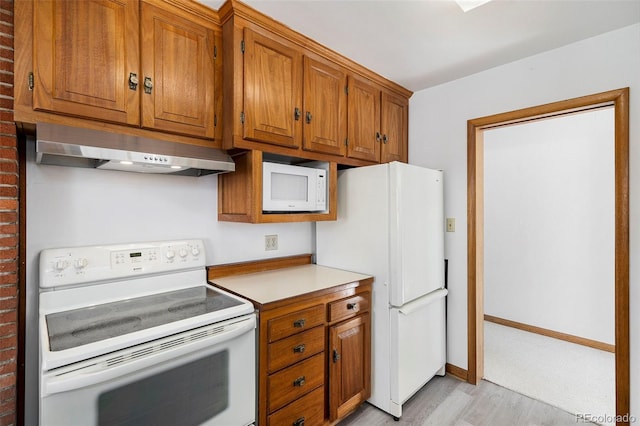 kitchen with white appliances, range hood, and light hardwood / wood-style floors