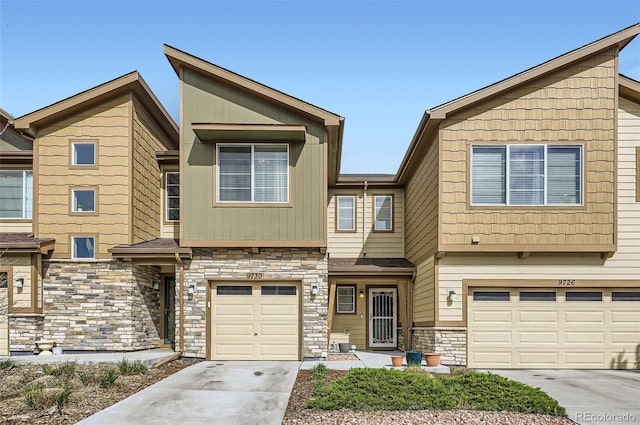 multi unit property featuring a garage, driveway, and stone siding