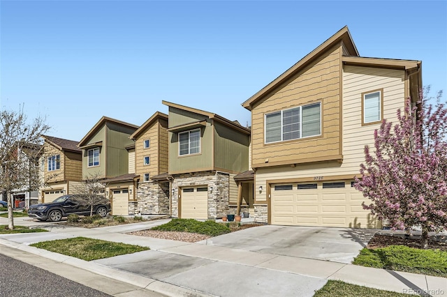 townhome / multi-family property featuring stone siding, driveway, a residential view, and a garage