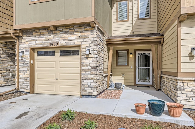 view of exterior entry with concrete driveway and stone siding