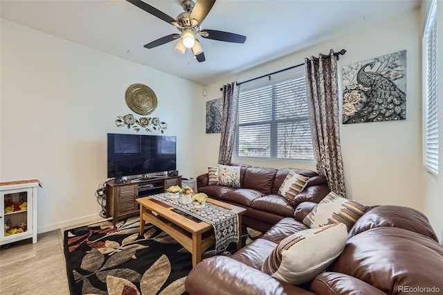 living room featuring light wood-style floors, a ceiling fan, and baseboards