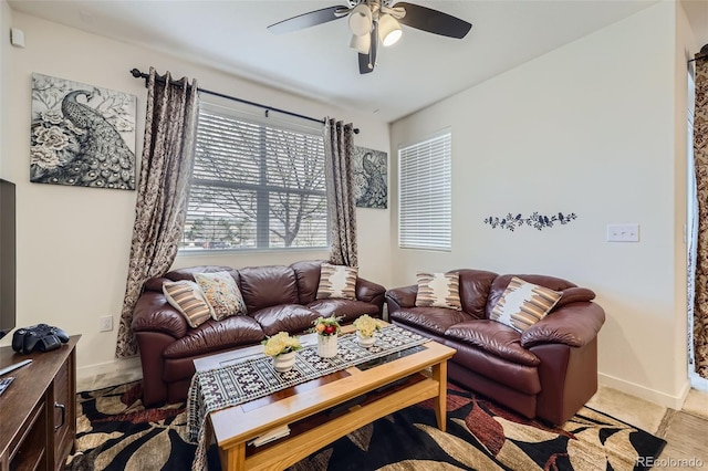 living area featuring a ceiling fan and baseboards