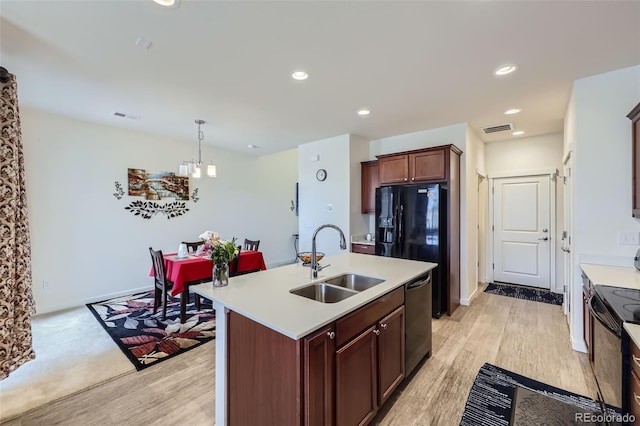 kitchen featuring light wood-type flooring, visible vents, a sink, and black appliances